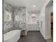 Modern bathroom featuring marble tile, double vanity, glass-enclosed shower and soaking tub at 712 Proud Eagle Ln, Las Vegas, NV 89144