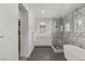 Modern bathroom featuring marble tile, double vanity, glass-enclosed shower and soaking tub at 712 Proud Eagle Ln, Las Vegas, NV 89144