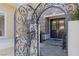 An ornate iron gate opens to a beautiful double door entry with stone steps and lush landscaping at 712 Proud Eagle Ln, Las Vegas, NV 89144
