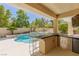 Inviting outdoor kitchen area with built-in bar and picturesque pool view at 712 Proud Eagle Ln, Las Vegas, NV 89144