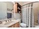 Cozy bathroom with wooden fixtures, decorative shelving, a shower with patterned curtains, and a sink at 8325 Villa De Medici St, Las Vegas, NV 89131