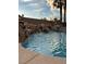 Beautiful pool featuring a rock waterfall and palm trees, perfect for relaxing and enjoying the backyard oasis at 8325 Villa De Medici St, Las Vegas, NV 89131