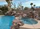 Inviting pool and spa with rock waterfall feature, complemented by lush landscaping and palm trees at 8325 Villa De Medici St, Las Vegas, NV 89131