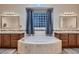 Luxurious bathroom featuring a soaking tub, dual vanities, decorative mirrors, and elegant lighting fixtures at 8705 Killians Greens Dr, Las Vegas, NV 89131