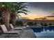 Inviting backyard oasis with a sparkling pool, spa, and lounge chairs against a backdrop of a desert sunset at 8705 Killians Greens Dr, Las Vegas, NV 89131