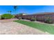 Manicured backyard features desert landscaping, green turf, and a brick-paved patio, ideal for relaxation at 9243 White Waterfall Ave, Las Vegas, NV 89149
