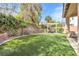 Spacious backyard features artificial grass, mature landscaping, and a cozy pergola seating area at 9465 Perennial View Ave, Las Vegas, NV 89148