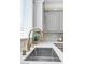 Detailed view of a kitchen sink with stylish faucet, white countertops, gray cabinets, and a bright, window-lit workspace at 9465 Perennial View Ave, Las Vegas, NV 89148