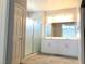 Bathroom with shower, frosted glass door, and dual sink vanity with white cabinets at 1064 Blue Wine Ct, Henderson, NV 89002