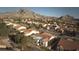 An aerial view highlights a home with mountain views in a well-maintained neighborhood with red tile roofs at 10717 Grand Cypress Ave, Las Vegas, NV 89134
