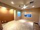 A cozy bedroom with neutral paint, carpet, and a ceiling fan, plus large windows for ample natural lighting at 10717 Grand Cypress Ave, Las Vegas, NV 89134