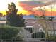 A stunning sunset view over the home's backyard showcasing beautiful skies, desert landscaping, and a well-maintained community at 10717 Grand Cypress Ave, Las Vegas, NV 89134