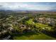 A neighborhood features lush golf course views, mature trees, and a backdrop of scenic mountains in an aerial shot at 11830 Kingsbarns Ct, Las Vegas, NV 89141