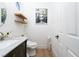 Stylish half-bathroom featuring modern toilet, floating shelves, unique artwork, and wood flooring at 11830 Kingsbarns Ct, Las Vegas, NV 89141