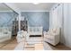 Inviting Bedroom featuring a cozy armchair, soft rug, crib, climbing structure, and blue paneled accent wall at 11830 Kingsbarns Ct, Las Vegas, NV 89141