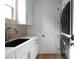 Functional laundry room with black sink, white cabinets, sleek faucet, and stacked washer and dryer units at 11830 Kingsbarns Ct, Las Vegas, NV 89141