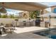 Outdoor kitchen and patio area with a grill, sink, seating, and a view of the pool at 11830 Kingsbarns Ct, Las Vegas, NV 89141