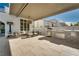 Inviting covered patio with stone floors, stylish outdoor kitchen, and comfortable seating area at 11830 Kingsbarns Ct, Las Vegas, NV 89141