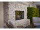 A stone fireplace with seating and greenery create an inviting outdoor space at 11830 Kingsbarns Ct, Las Vegas, NV 89141