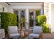 Charming patio space with two cushioned chairs and lush, green landscaping at 11830 Kingsbarns Ct, Las Vegas, NV 89141