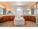 Main bathroom with tub, cherry wood cabinets, neutral tile and dual sinks at 1291 Rolling Sunset St, Henderson, NV 89052