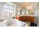 Bright main bathroom featuring a garden tub, large window, and a dual sink vanity at 1291 Rolling Sunset St, Henderson, NV 89052