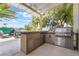 Outdoor kitchen under a pergola featuring a built-in grill and prep area for entertaining at 1291 Rolling Sunset St, Henderson, NV 89052