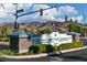 Community entrance with attractive signage, landscaping, and mountain views under a blue sky at 2103 Poppywood Ave, Henderson, NV 89012