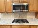 This kitchen features wood cabinets, granite countertops, stainless steel appliances, and a cooktop with overhead microwave at 2138 Fort Halifax St, Henderson, NV 89052