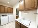 A laundry room features oak cabinets, a sink, and modern washer and dryer at 2138 Fort Halifax St, Henderson, NV 89052