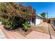A quaint backyard featuring colorful flowers and a palm tree, complemented by red brick trim, gravel, and a fence at 2600 E Owens Ave, North Las Vegas, NV 89030