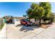 Charming single-story home featuring a large driveway, mature tree, and a red SUV parked out front on a sunny day at 2600 E Owens Ave, North Las Vegas, NV 89030