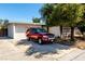 Charming single-story home featuring a large driveway, mature tree, and a red SUV parked out front on a sunny day at 2600 E Owens Ave, North Las Vegas, NV 89030