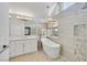 Bright and modern bathroom featuring a free-standing tub, large mirror and stone floors at 3165 S Monte Cristo Way, Las Vegas, NV 89117