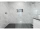 Modern shower featuring marble tile walls, a rain shower head, and black hexagon tile flooring at 3905 Casa Grande Ave, Las Vegas, NV 89102