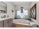 Relaxing bathroom with a soaking tub, stylish vanity, decorative mirror, and tiled surround at 4185 W Arby Ave, Las Vegas, NV 89118