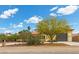 Landscaped front yard of a single-story home with a gray three-car garage, with multiple desert trees at 4185 W Arby Ave, Las Vegas, NV 89118