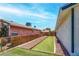 Backyard features a strip of artificial grass, rock landscaping, and a wood fence for outdoor enjoyment at 4432 Ash Ave, Las Vegas, NV 89110