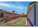 Narrow backyard with artificial grass, gravel area, bordered by wooden and chain-link fence at 4432 Ash Ave, Las Vegas, NV 89110