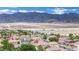 Expansive aerial view of a neighborhood with mountain backdrop and blue sky above homes with red tile roofs at 4909 Cherokee Run Ct, Las Vegas, NV 89131