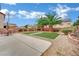 Large backyard featuring concrete patio, decorative rocks, two palm trees, manicured grass patches, and outdoor seating at 4909 Cherokee Run Ct, Las Vegas, NV 89131