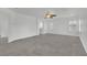 A spacious bedroom featuring neutral carpet, white walls, a ceiling fan, and a view to a bathroom at 4909 Cherokee Run Ct, Las Vegas, NV 89131