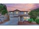 Two-story home with a well-maintained front yard, two-car garage, and a red tile roof at sunset at 4909 Cherokee Run Ct, Las Vegas, NV 89131