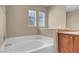 Bright bathroom featuring a soaking tub, neutral colors, and natural light from two windows at 6599 Netherseal Ave, Las Vegas, NV 89139