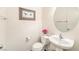 Powder room featuring a pedestal sink, toilet, and round mirror at 6623 Hurkling Stone Ave, Las Vegas, NV 89139