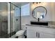 Modern bathroom featuring a glass shower, hexagonal tiles, and a sleek round mirror at 6736 Quinella Dr, Las Vegas, NV 89103