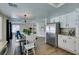 Bright dining area featuring a modern chandelier, white chairs, and adjacent kitchen with stainless steel appliances at 6736 Quinella Dr, Las Vegas, NV 89103