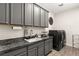 Well-equipped laundry room with gray cabinets, granite countertops, and modern appliances at 7165 N Grand Canyon Dr, Las Vegas, NV 89149