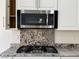 Close-up of kitchen features including cooktop, microwave, and custom backsplash at 7246 Spring Flower Ave, Las Vegas, NV 89117