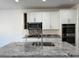 Kitchen island with granite countertops, white cabinets, stainless steel microwave and cooktop at 7246 Spring Flower Ave, Las Vegas, NV 89117